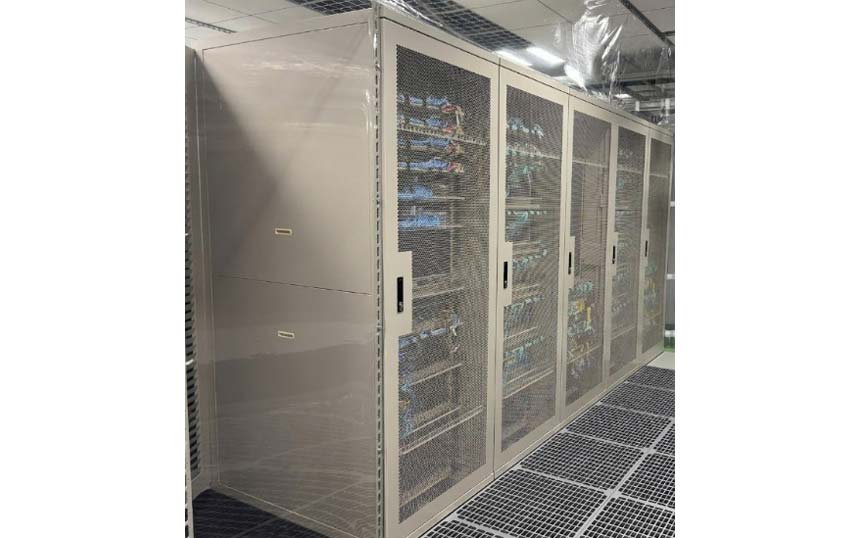 Row of tall metal server cabinets with mesh doors in a data center; equipment and cables visible inside.