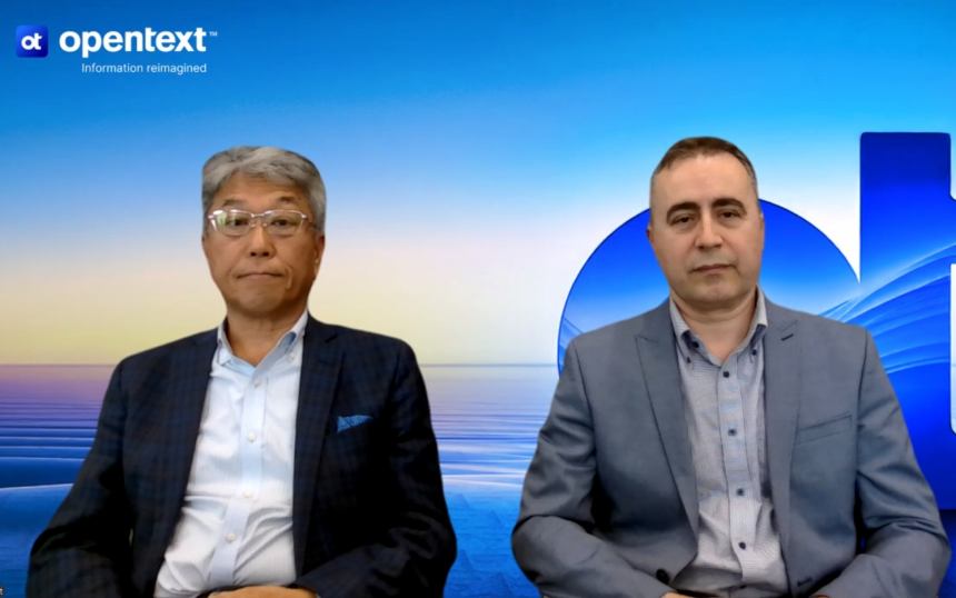 Two men in business suits seated side by side in front of a blue OpenText backdrop with the logo visible.