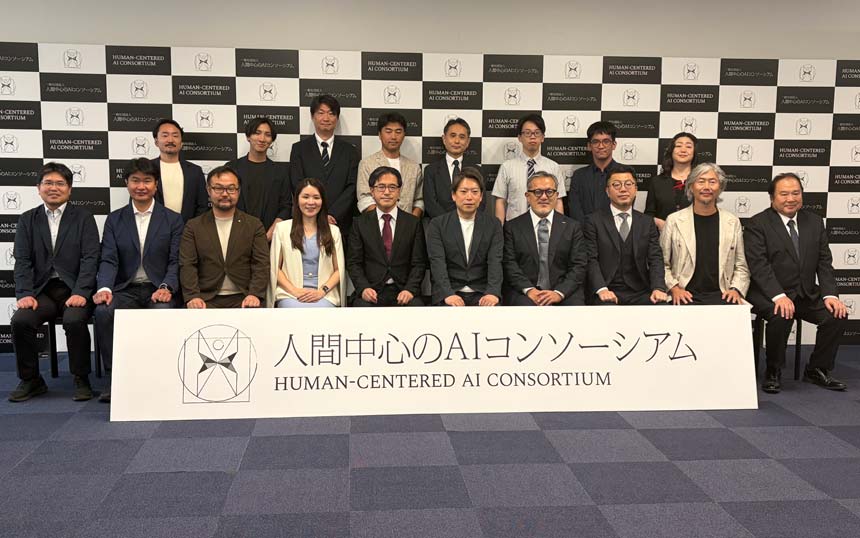 Group of professionals in suits posing for a photo behind a banner reading 'Human-Centered AI Consortium'.