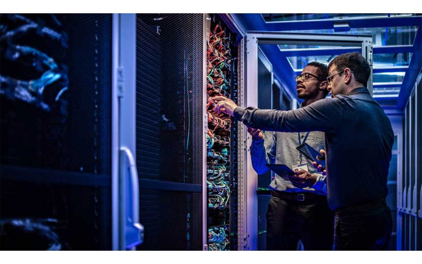 データセンター内のサーバーラックに設置されたネットワーク機器を確認する2人の技術者のイメージ画像