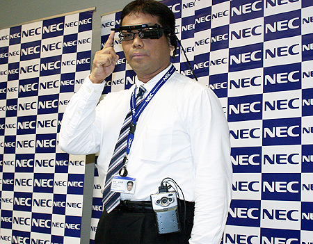 Tele Scouterを装着したNEC プラットフォームマーケティング戦略本部 マネージャーの永浜公太郎氏。ベルトに装着しているのが小型コンピュータ